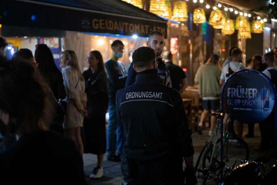 Ein Polizeibeamter und ein Mitarbeiter des Ordnungsamtes stehen vor einem Lokal in Berlin.