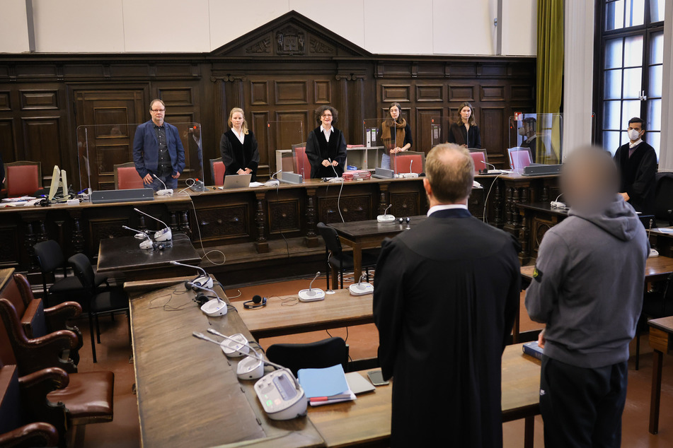 Der Angeklagte und sein Anwalt stehen vor Ulrike Schönfelder (hinten, 3.v.l.), Vorsitzende Richterin am Landgericht. Die Staatsanwaltschaft rechnet den Angeklagten aufgrund früherer Verfahren den Hells Angels zu.