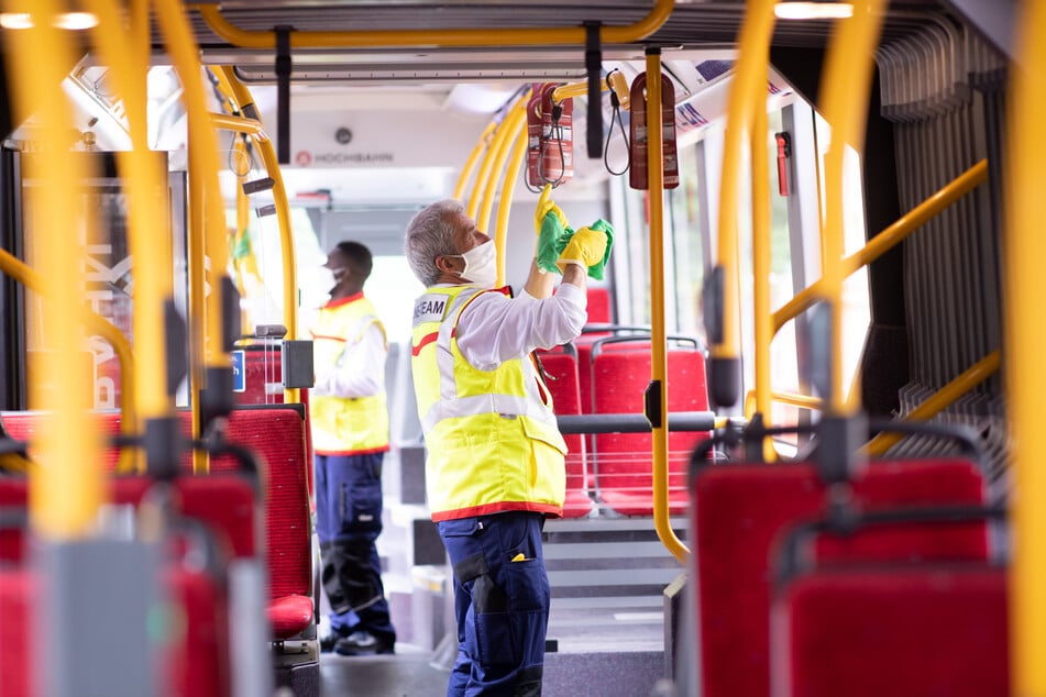 Mehmet Ince (r) und Abdul Razak Alidu, Mitarbeiter eines Hygieneteams von Tereg für die Hamburger Hochbahn, arbeiten in einem Gelenkbus während einer Standpause am Bahnhof Altona.