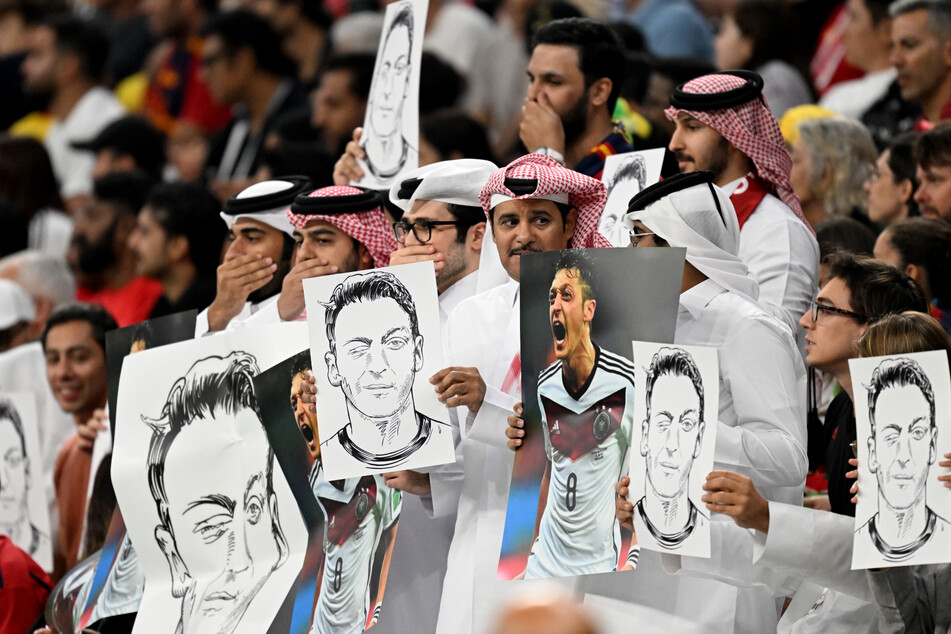 Katarische Fans halten Bilder des ehemaligen Nationalspielers Mesut Özil hoch, damit wollen sie offenbar ihr Unbehagen gegenüber "deutscher Doppelmoral" ausdrücken.