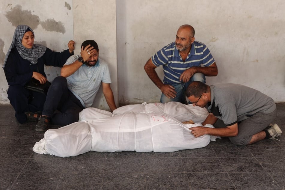 Palestinians mourn by the bodies of relatives killed in Israeli military operations in northern Gaza, at Al-Ahli Arab hospital in Gaza City on October 21, 2024.