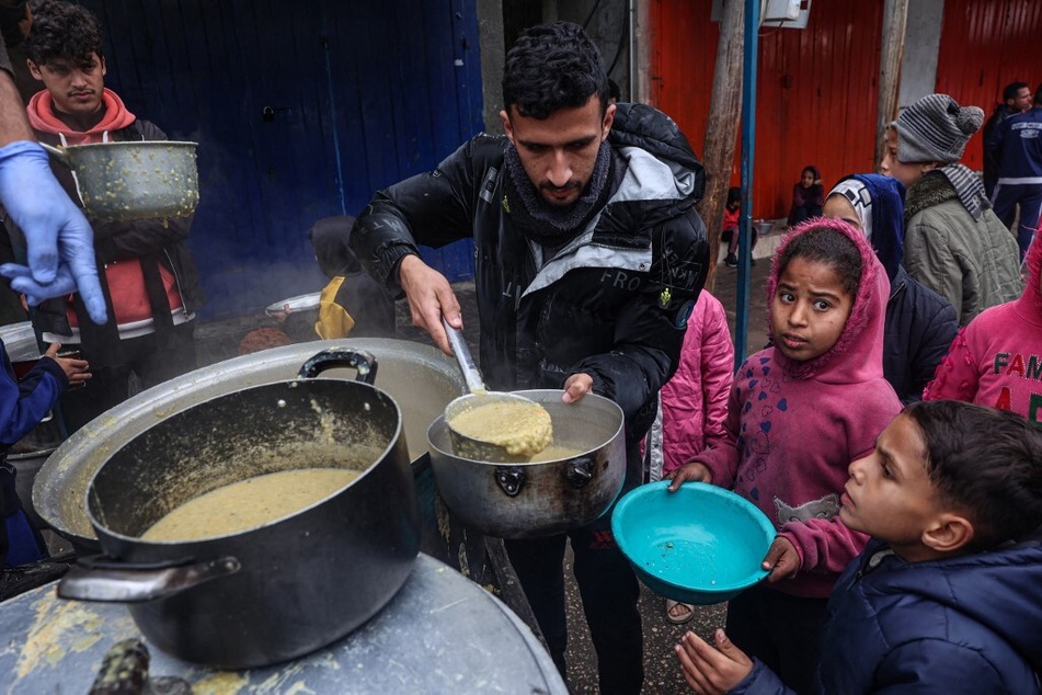 A volunteer distributes rations of red lentil soup to displaced Palestinians in Rafah in the southern Gaza Strip on February 18, 2024.