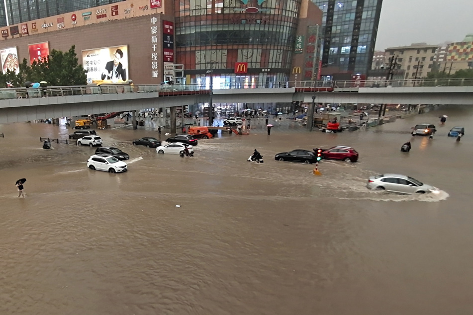 Fahrzeuge stehen in der zentralchinesischen Provinz Henan auf einer überfluteten Straße.