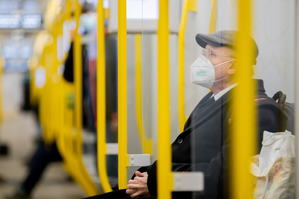Ein Mann sitzt mit FFP2-Maske in der U-Bahn.