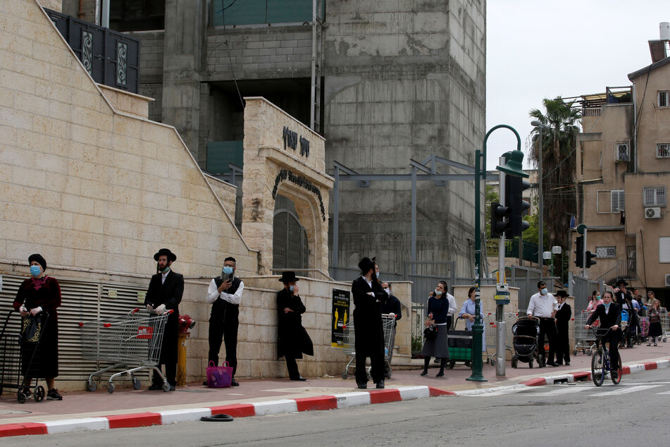 In der israelischen Stadt Bnei Berak warten Menschen mit Schutzmasken und Sicherheitsabständen in einer Schlange.