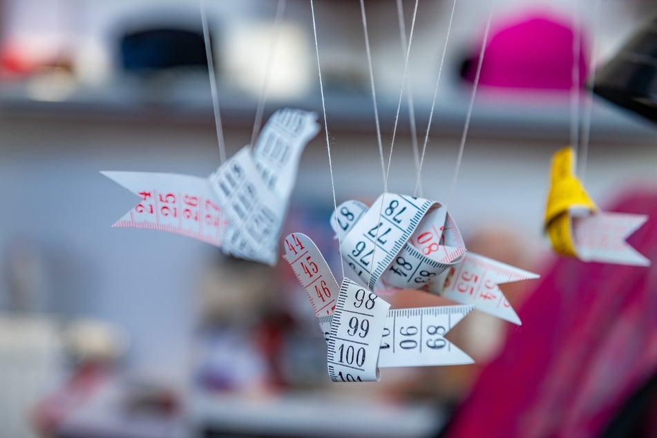 Kleine Vögel aus Maßbändern "zwitschern" am Arbeitsplatz im Atelier.