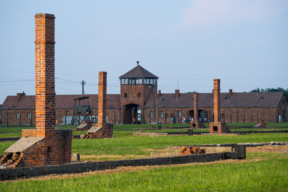 Blick auf das historische Tor (Innenseite) und die Schornsteine der Baracken im früheren Vernichtungsslager Auschwitz-Birkenau.