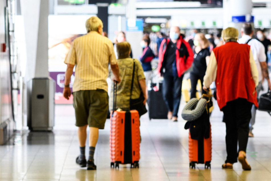 Reisende gehen Anfang Juli am Flughafen Frankfurt mit Gepäck durch die Abflughalle im Terminal 1.