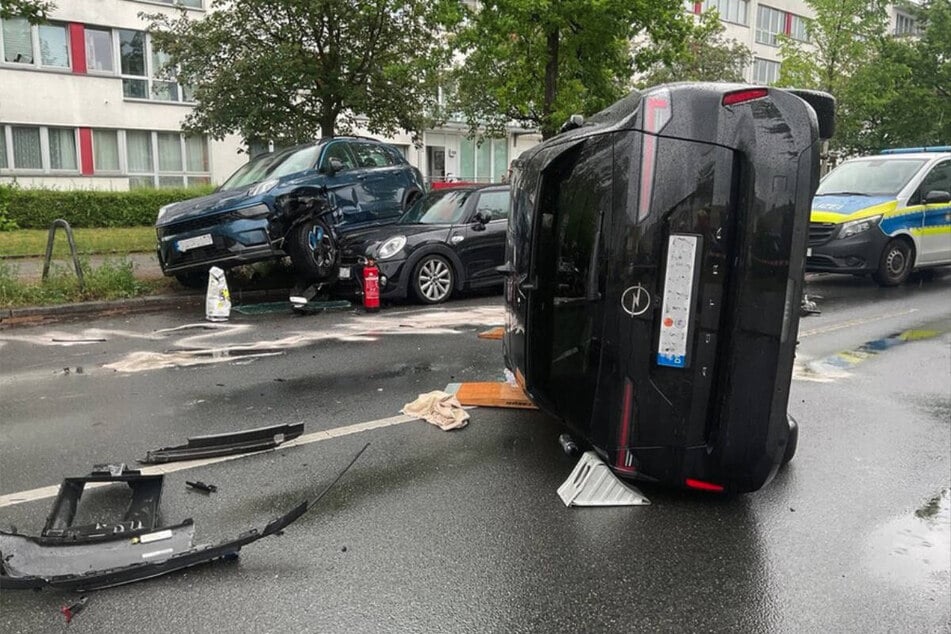 Der Opel ist nach dem Zusammenprall auf die Fahrerseite gekippt. Im Hintergrund sind zwei parkende Autos zu sehen, die bei dem Unfall aufeinander gewoben worden sind.