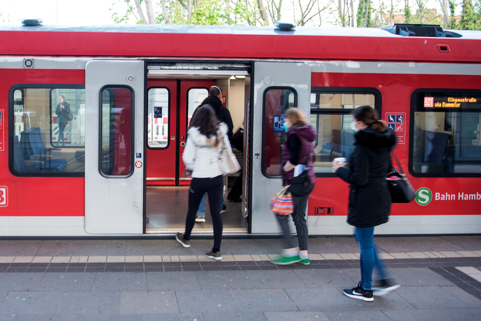 Fahrgäste mit einem Mund-Nasen-Schutz steigen an einem Bahnhof in eine S-Bahn ein.