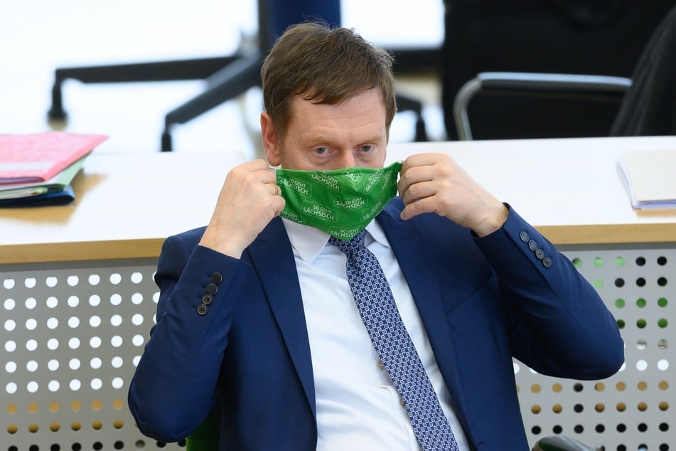 Michael Kretschmer (CDU), Ministerpräsident von Sachsen, hält im Plenum einen Mund-Nasen-Schutz bei der Landtagssitzung.