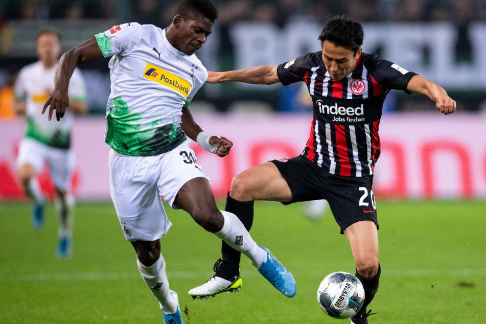 Gladbachs Breel Embolo (l) und Frankfurts Makoto Hasebe kämpfen um den Ball: Die geplante Revanche für die Hinspiel-Niederlage (2:4) gegen Borussia Mönchengladbach am Sonntag wird ohne Publikum ausgetragen.