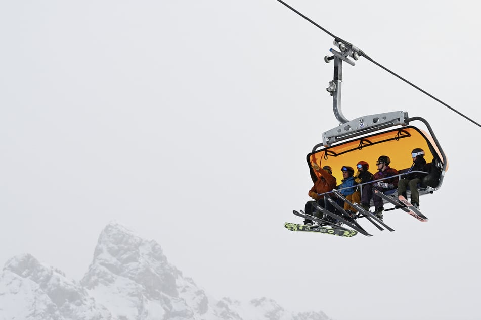 Skifahrer fahren beim Skisaisonstart mit dem Lift auf die Piste an der Zugspitze.