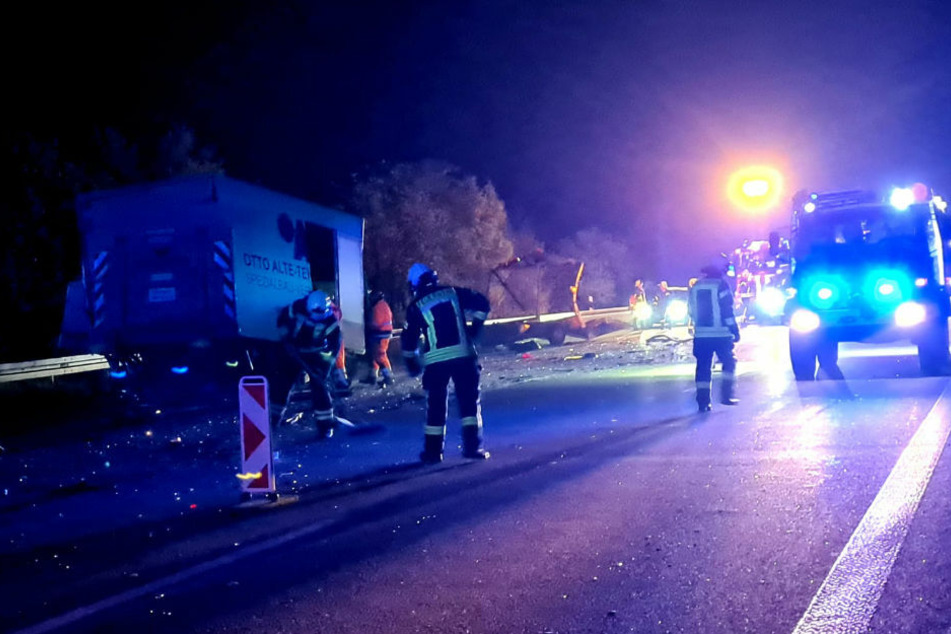 Feuerwehrleute helfen dabei, die Trümmerteile von der Fahrbahn zu entsorgen.