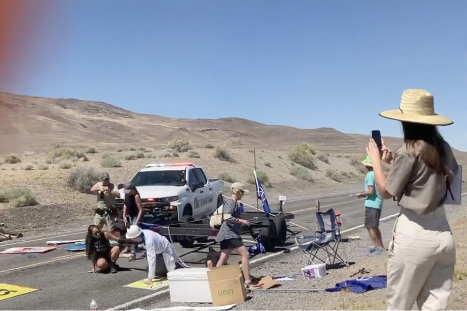 A police officer draws his gun and orders the climate activists to lie on the ground.