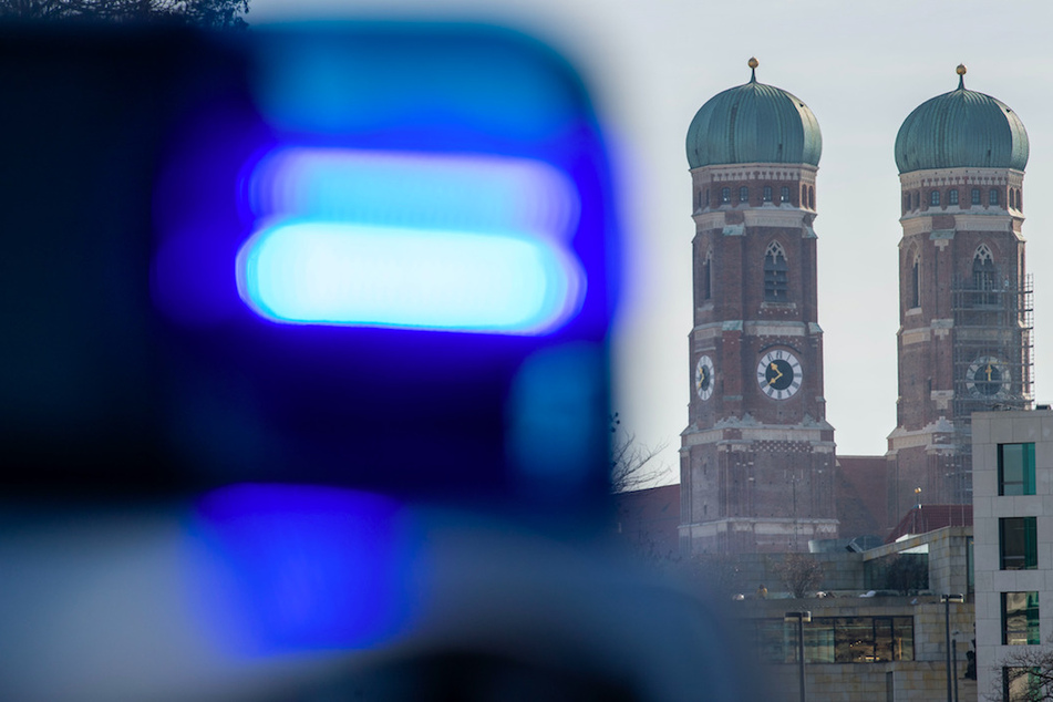 Ein Blaulicht einer Polizeistreife ist vor den Türmen der Frauenkirche zu sehen. (Symbolbild)