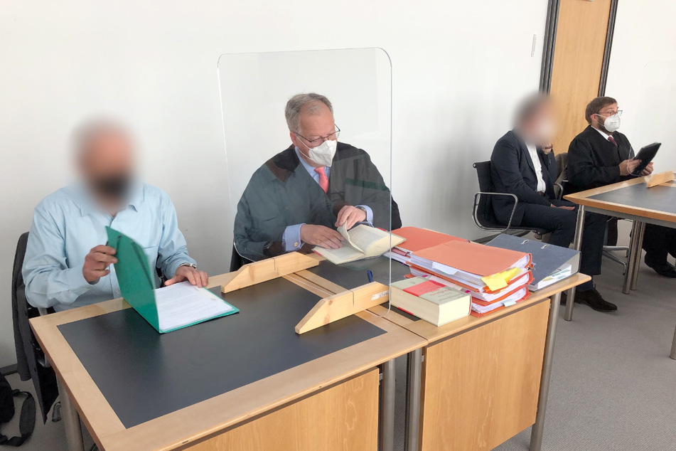 Die Angeklagten (1.v.l. sowie 3.v.l.) sitzen mit ihren Verteidigern vor dem Start der Verhandlung im Gerichtssaal des Amtsgerichts.