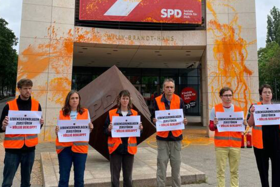 Klimaaktivisten der "Letzten Generation" stehen vor der besprühten SPD-Parteizentrale in Berlin.