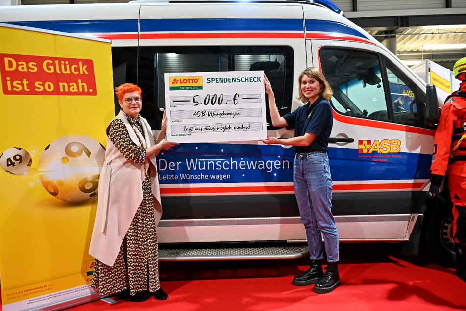 TAG24-Reporterin Katrin Koch (l.) übergibt als "Sachsenlotto-Möglichmacher" einen Scheck an ASB-Wünschewagen-Koordinatorin Lea Sellnau (27).