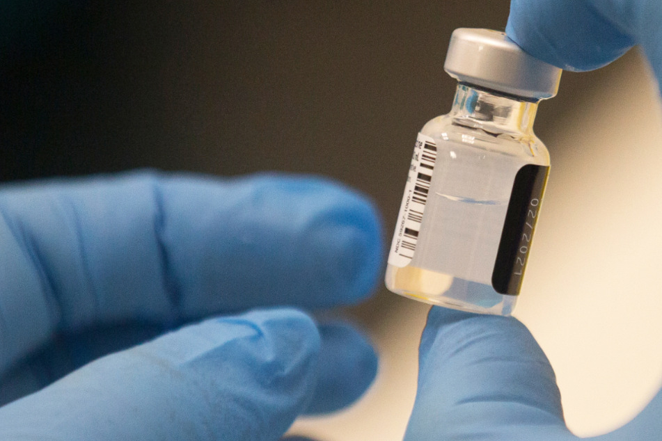 Ein Arbeiter hält eine Ampulle des Pfizer-BioNTech COVID-19-Impfstoffs in der Hand.
