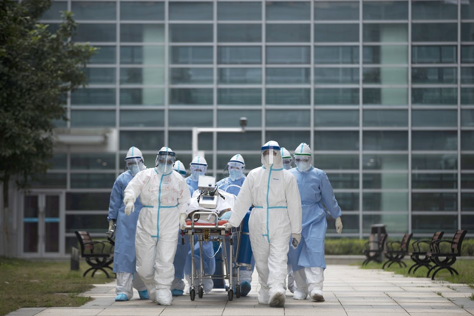 Medizinisches Personal in Schutzkleidung transportiert einen COVID-19-Patienten in den CT-Raum eines Krankenhauses.