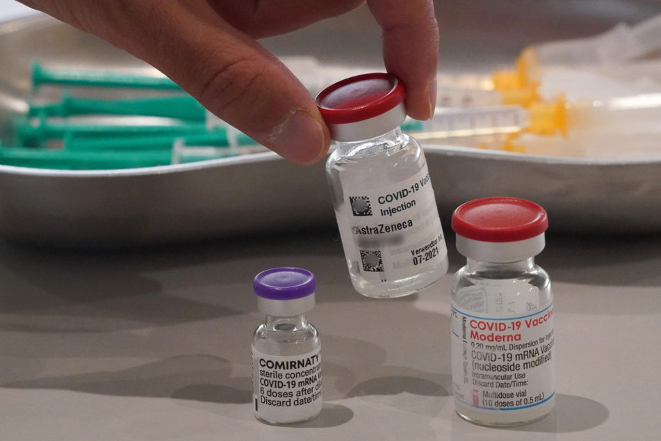 Ein Mitarbeiter des Impfzentrums in den Messehallen nimmt eine Impfdose vom Impfstoff Astrazeneca vom Tisch.