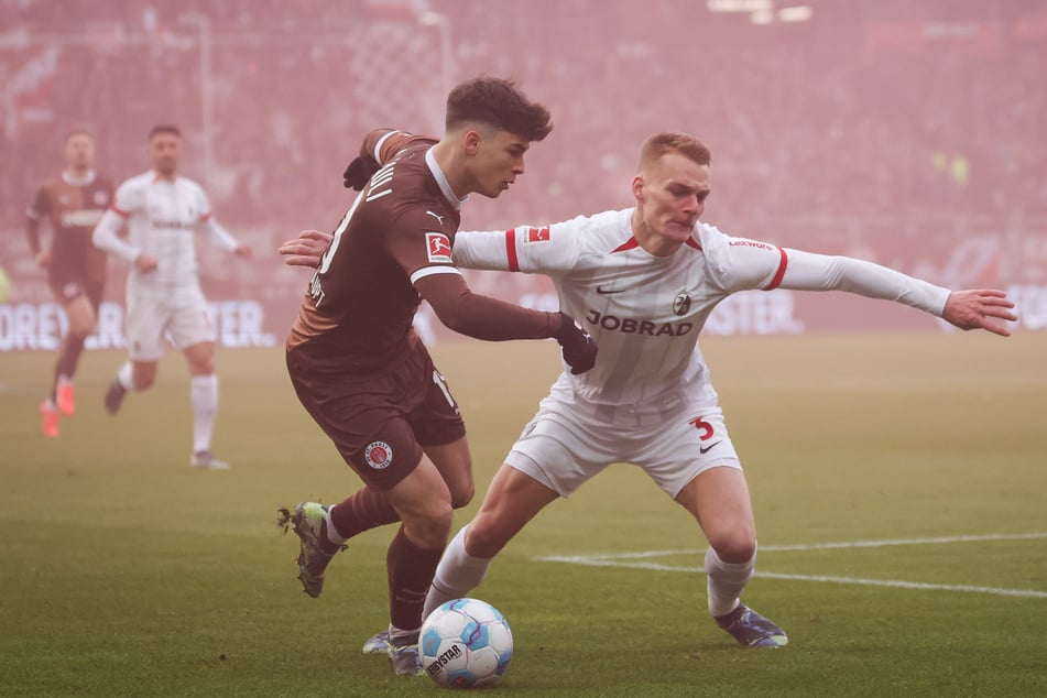 Kurz nach Anpfiff war das Millerntor vernebelt. FCSP-Profi Noah Weißhaupt (l) und SC-Verteidiger Philipp Lienhart ließen sich davon nicht beeinflussen.