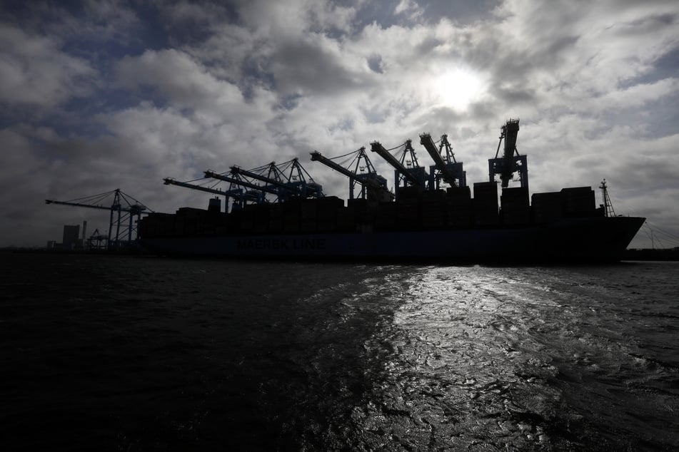 Die Silhouette eines Containerschiffes zeichnet sich im Hafen von Rotterdam gegen die Sonne ab.