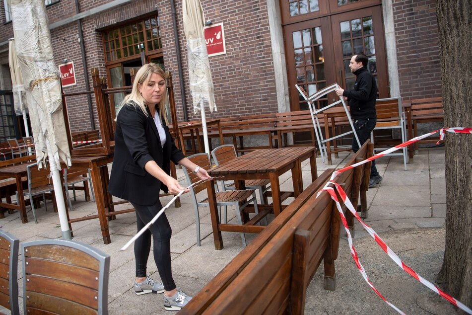 Vor der Wiedereröffnung des Bremer Restaurants werden mit einem Zollstock die Abstände zwischen Tischen und Stühlen vermessen.