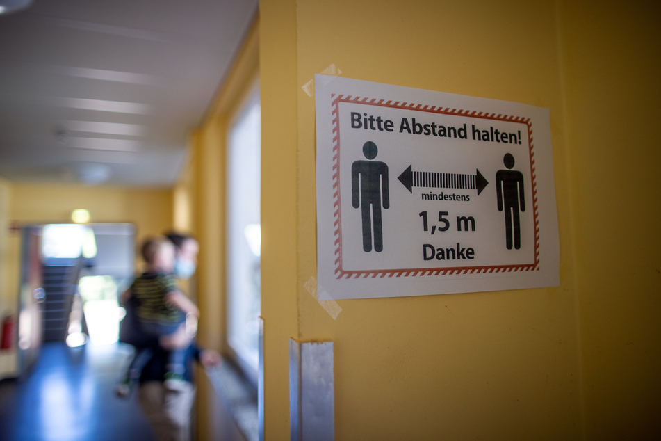 Ein Hinweisschild auf die Sicherheitsabstände als Corona-Schutzmaßnahme hängt in einem Schulflur.