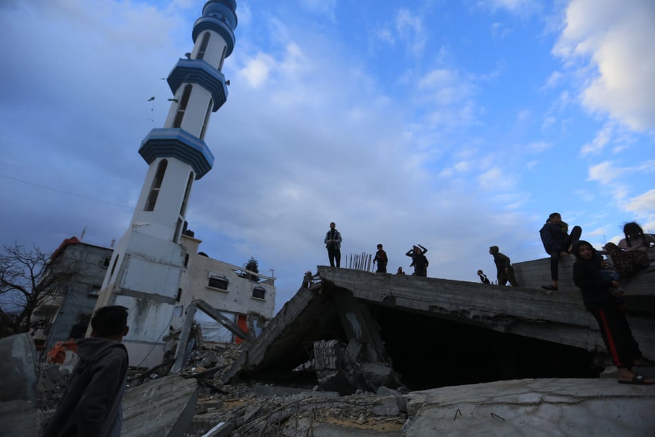Muslime stehen auf den Ruinen der zerstörten Al-Farouq-Moschee in Rafah, nachdem sie das Eid al Fitr-Gebet verrichtet haben.