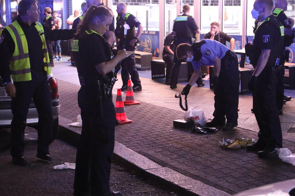 Polizisten einer Einsatzhundertschaft suchen den Tatort auf der Sonnenallee in Berlin-Neukölln ab.