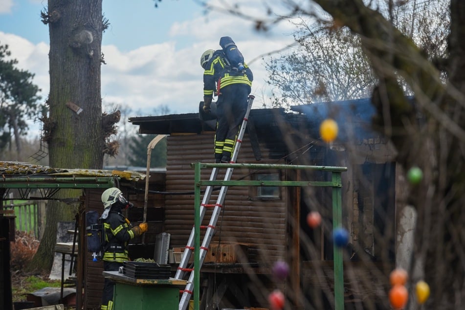 Die Feuerwehrleute löschten das Feuer der brennenden Laube. Dabei mussten sie Atemschutz-Masken tragen.