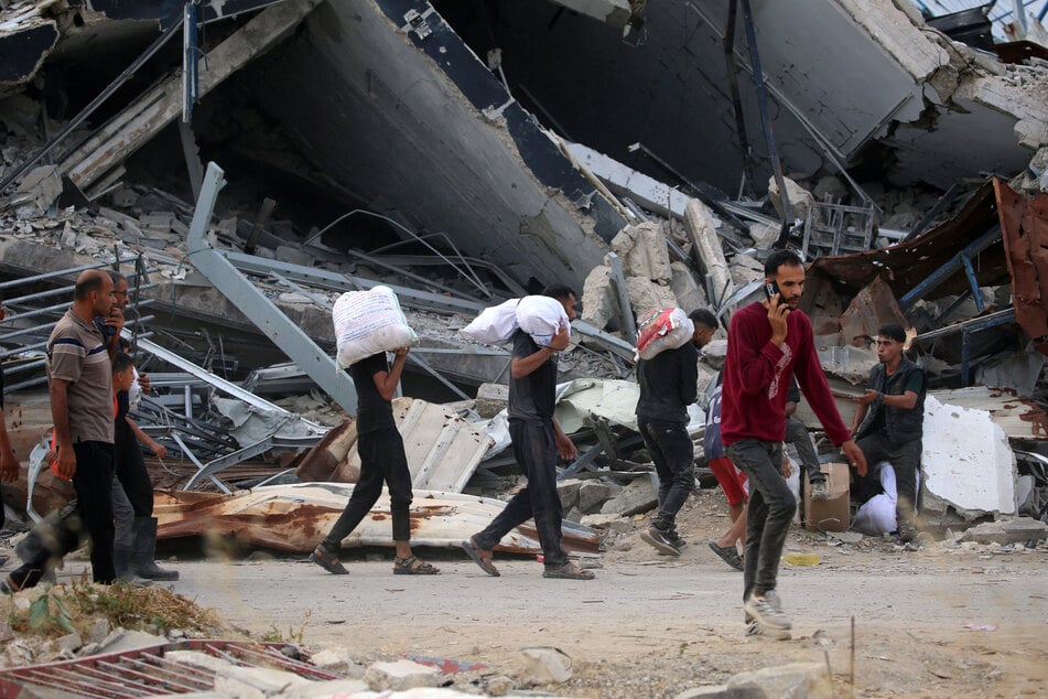 Displaced Palestinians carry relief supplies from the Gaza Humanitarian Foundation in the central Gaza Strip on June 8, 2025.
