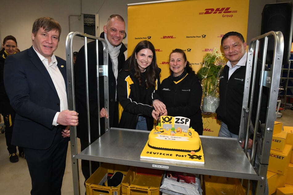 Oberbürgermeister Dr. Sven Mißbach (Freie Wähler, v.l.n.r), Landrat Ralf Hänsel (CDU), Regionalleiterin Paula Schöne, Heike Grafe aus Adelsdorf (hat die Torte zu Eröffnung gebacken und ist gelernte Bäckerin) sowie Niederlassungsleiter Kim Maulitz haben zur Eröffnung des Standorts eine schicke Post-Torte angeschnitten.