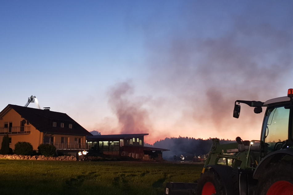 Ein Traktor steht vor dem brennenden Hof.