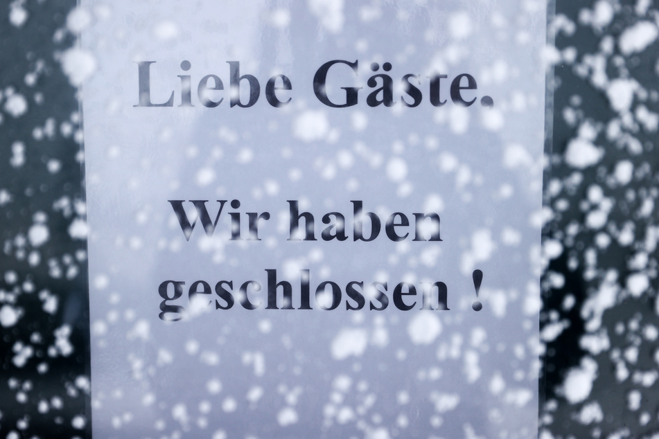 Ein Schild "Liebe Gäste, wir haben geschlossen!" hängt in einem verschneiten Kasten an einem Restaurant auf dem Fichtelberg.