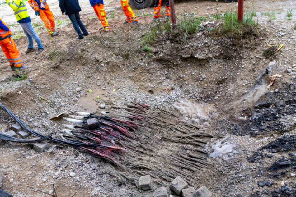 Arbeiter stehen an einer Stelle auf einer Baustelle, an der in der vorhergegangenen Nacht ein Kabelbrand ausgebrochen war.