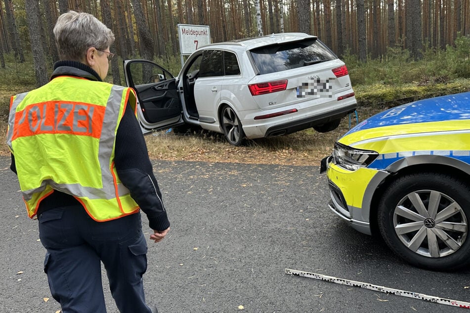 Während der Audi auf dem Zaun parkt, sind Auswirkungen des Aufpralls an der Front des Streifenwagens zu sehen.