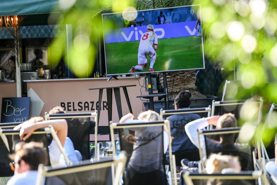 Zahlreiche Menschen sitzen auf Liegestühlen am Sonntagabend im James-Simon-Park und schauen sich ein Spiel der Fußball-EM an.