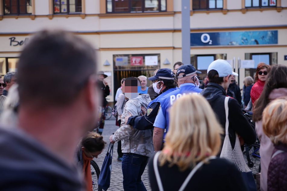 Beamte der Polizei während sie den Mann beiseite nehmen, der zuvor versucht hatte, eine Rede zu halten und nach einer Absage durch die Organisatoren aggressiv geworden war.