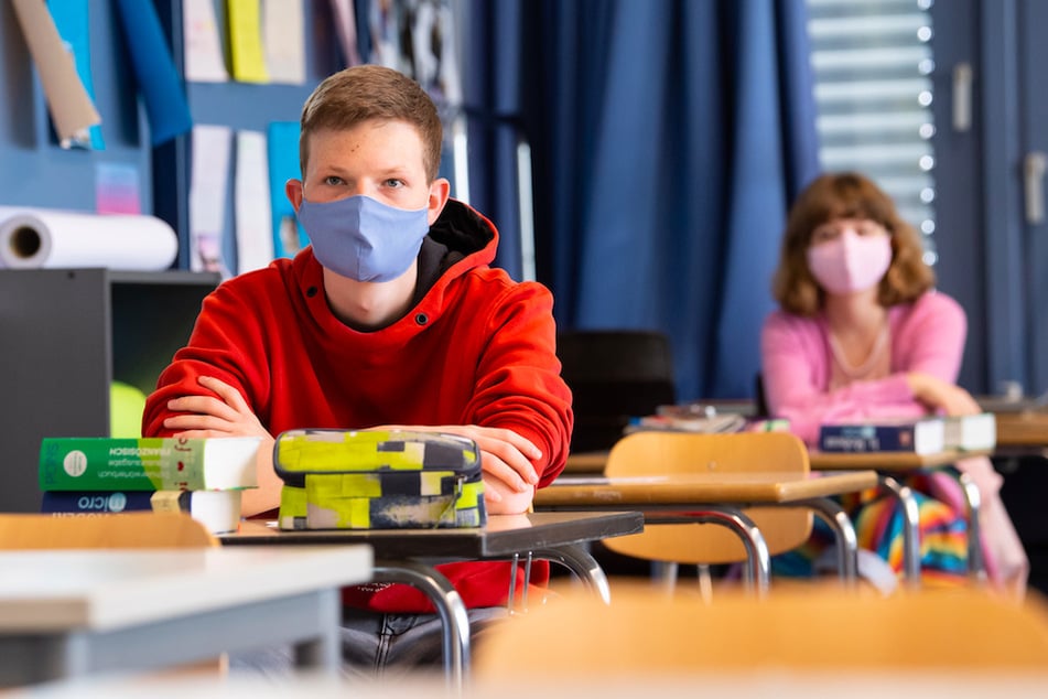 Schüler und Schülerinnen einer 12. Klasse nehmen am Unterricht teil und tragen Mundschutze. (Symbolbild)