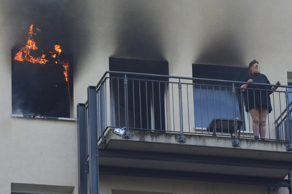 Eine Bewohnerin des Mehrfamilienhauses flüchtete vor dem Feuer auf den Balkon. Die Einsatzkräfte mussten sie jedoch durch die brennende Wohnung ins Freie bringen.