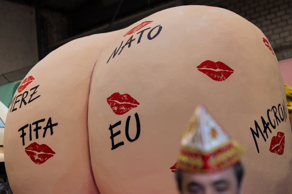 Ein Rosenmontagswagen zeigt Donald Trumps (79) Hintern mit Küssen übersät, unter anderem von Merz, Macron und der NATO.