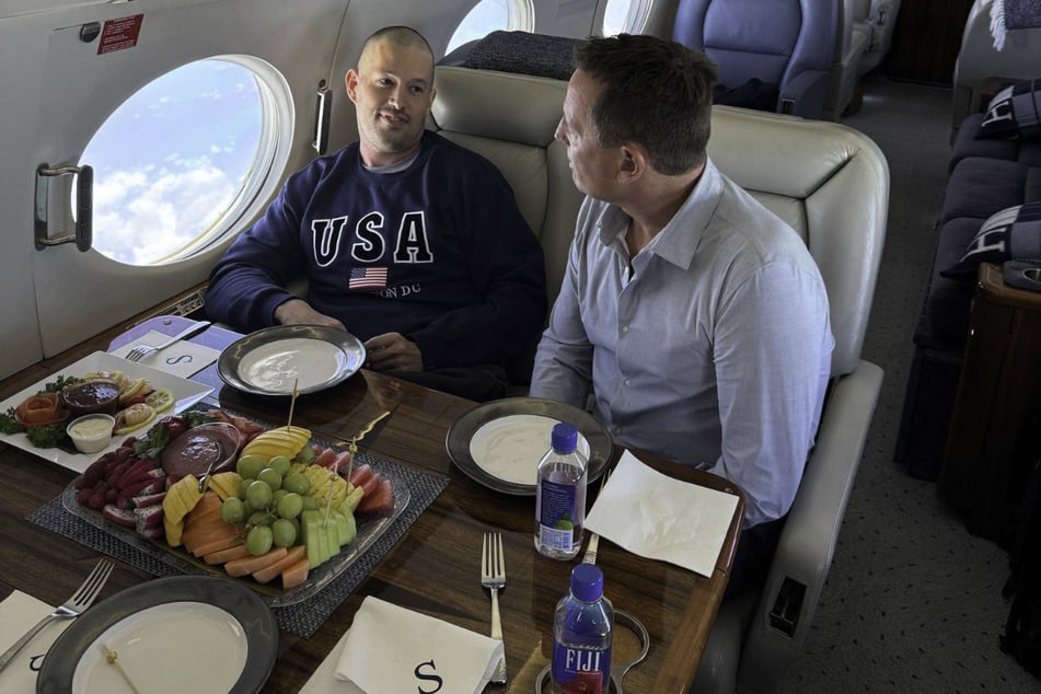 Richard Grenell (r.) speaks with Joe St. Clair in a plane as he returns to the US.