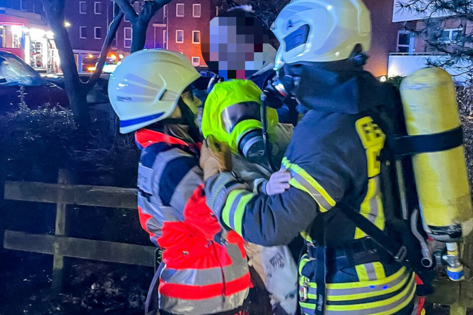 Feuerwehrleute retten ein Kind aus dem verrauchten Gebäude.