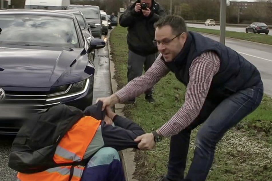 Ein wütender Autofahrer zerrt einen Aktivisten in Dresden von der Straße.