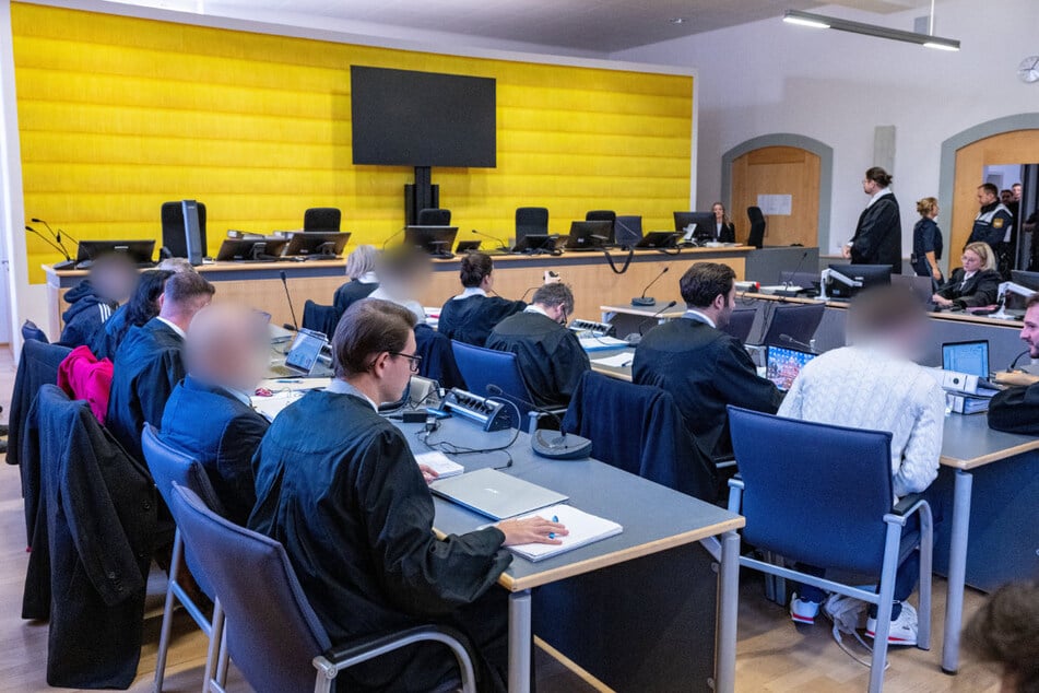 Die vier Angeklagten sitzen im Verhandlungssaal des Landgerichts Regensburg zwischen ihren Anwälten.