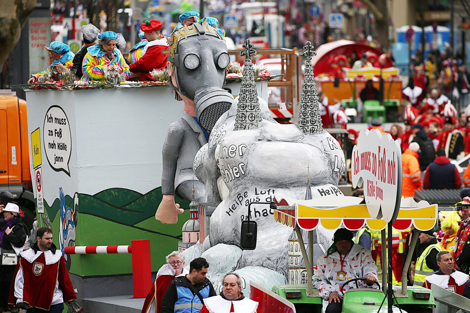 Ein Mottowagen zum Thema Luftverschmutzung in den Städten fährt im Rosenmontagsumzug in Köln mit.