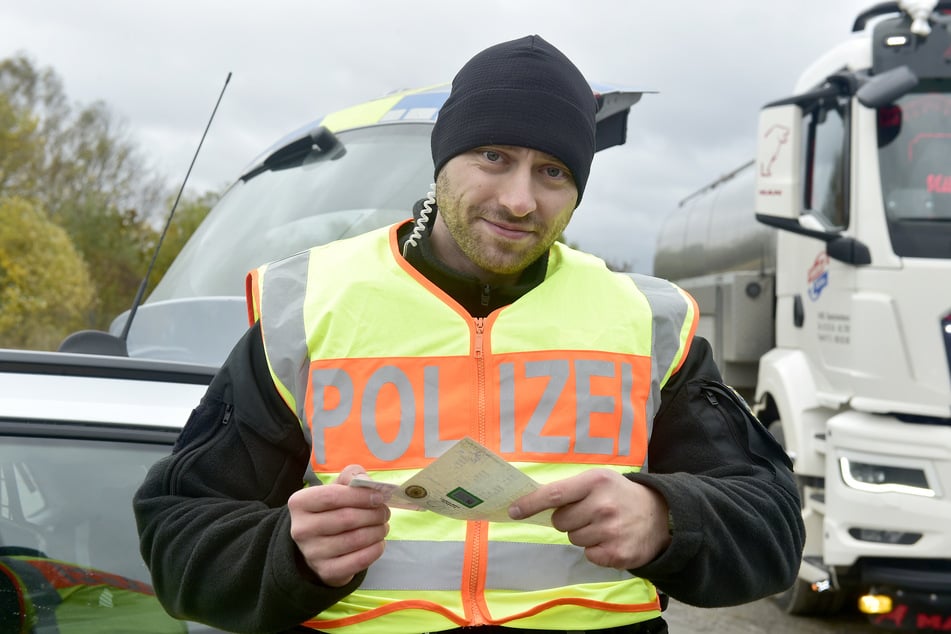 Polizeikommissar Toni Mann (34) hält Fahrzeugpapiere in der Hand.
